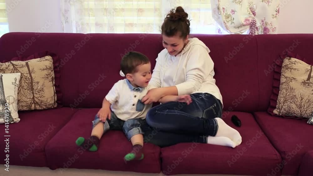 Little boy with his mother sitting in the room on the couch and watch TV Little boy with his mother sitting in the room on the couch and watch TV