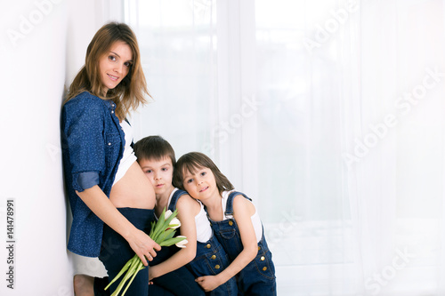 Pregnant mother, hugging her children, receiving tulips, flowers for holiday, back light