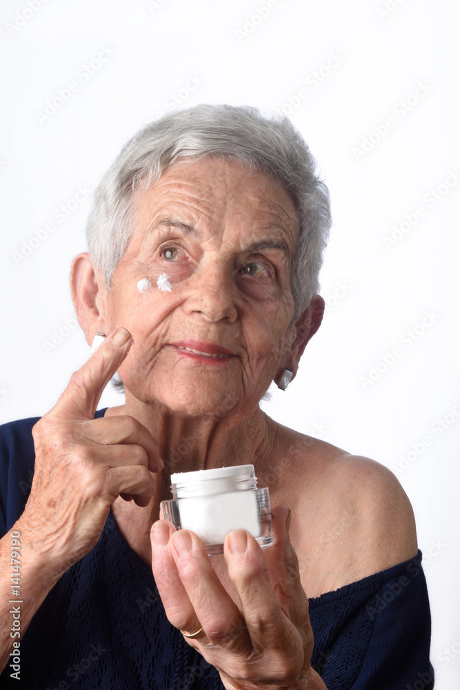 Senior woman applying skin cream or moisturiser to her face Senior woman applying skin cream or moisturiser to her face