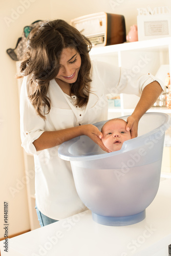 Mother washing baby in bath tub