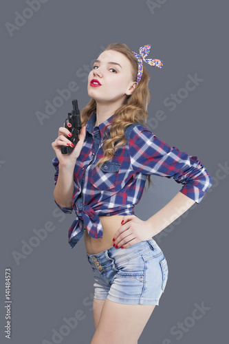  American attractive young woman with gun in front of US flag 