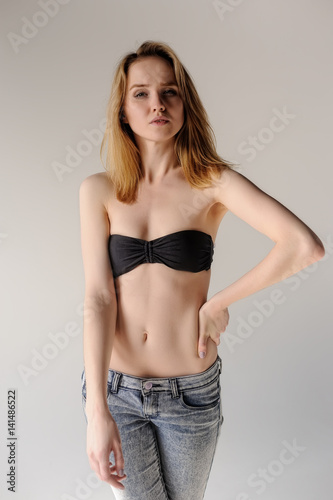 Pretty young blonde in black bra and jeans