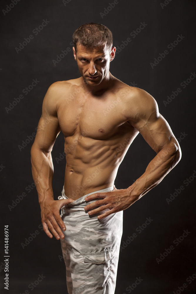Fototapeta premium half-naked handsome and muscular young man posing on a dark background