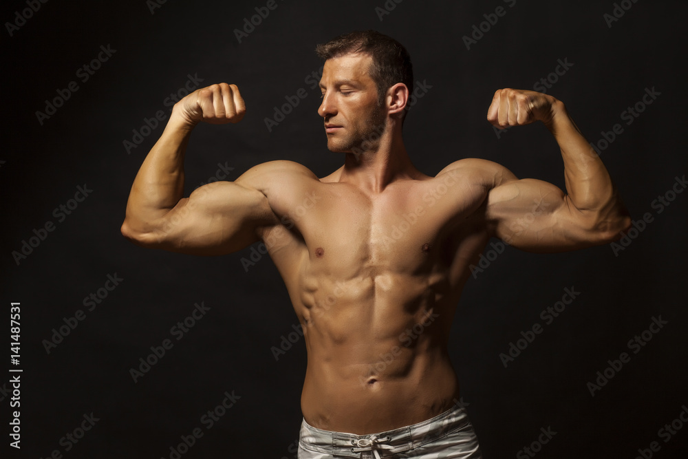 half-naked handsome and muscular young man posing on a dark background