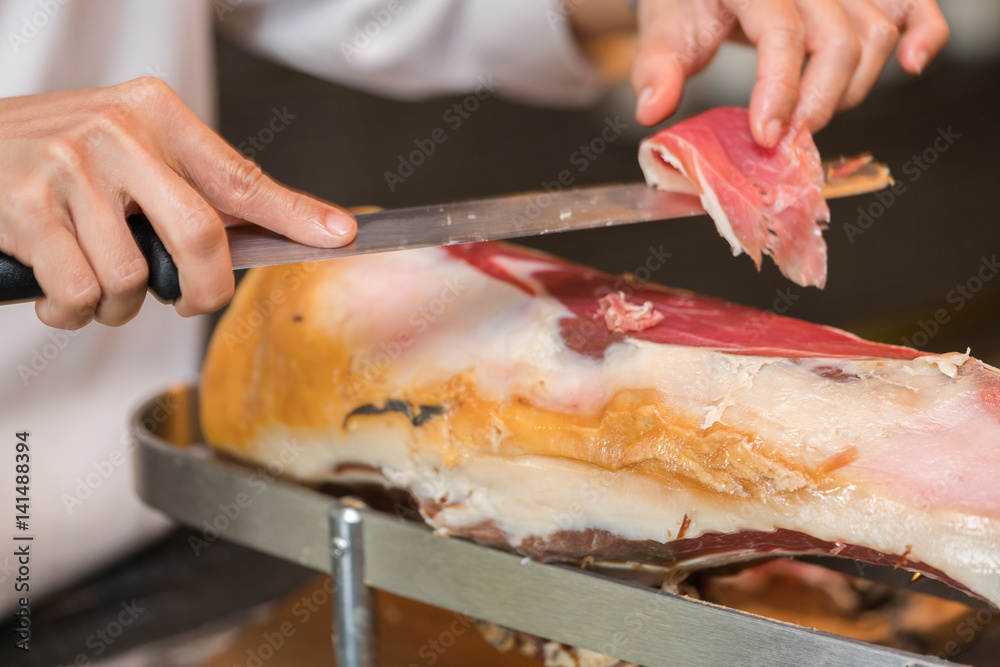 Chef slices serrano ham.