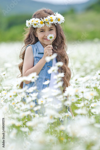 Beautiful little girl on nature with flowers 