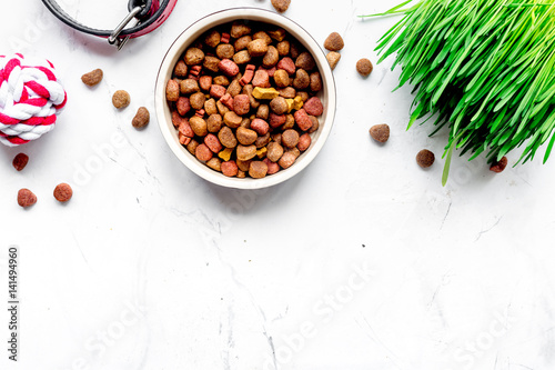 dry dog food in bowl on stone background top view
