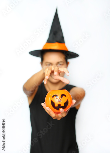 Young woman in witches hat and costume holding Jack pumpkin on a white background. Blur of Halloween Witch focus at Pumpkin.
