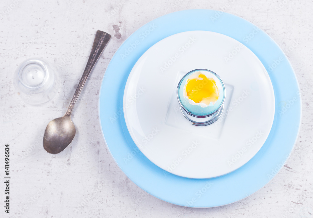 blue easter egg with yellow yolk, spoon, top view on wooden aged table - easter breakfast concept blue easter egg with yellow yolk, spoon, top view on wooden aged table - easter breakfast concept