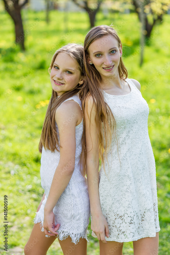 Two beautiful young girls in white dresses in summer Two beautiful young girls in white dresses in summer