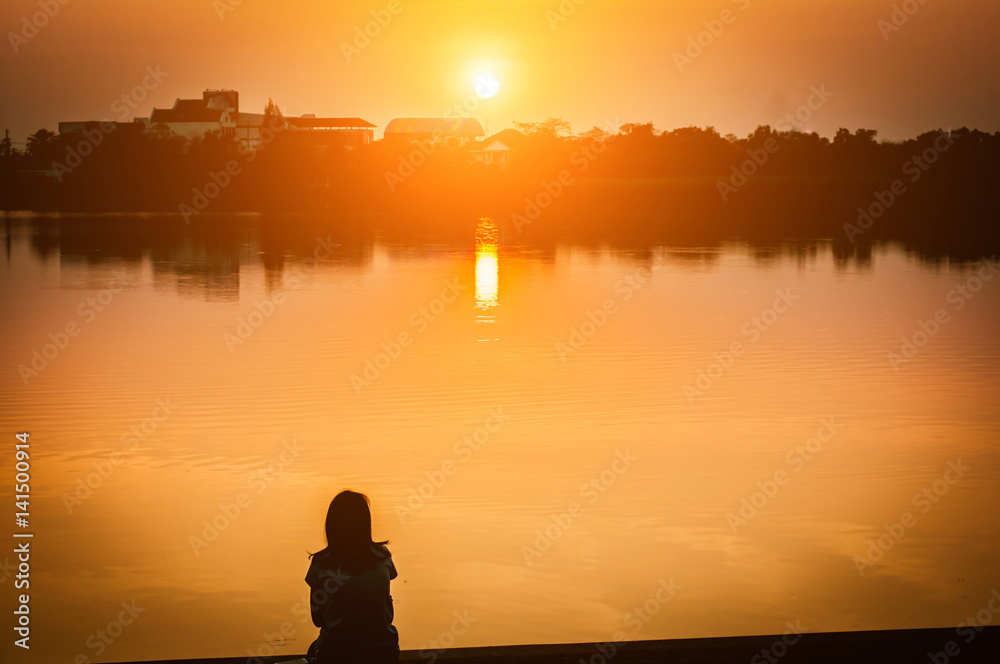 Woman sit near lake at sunset/ sunrise,selective focus,silhouette.