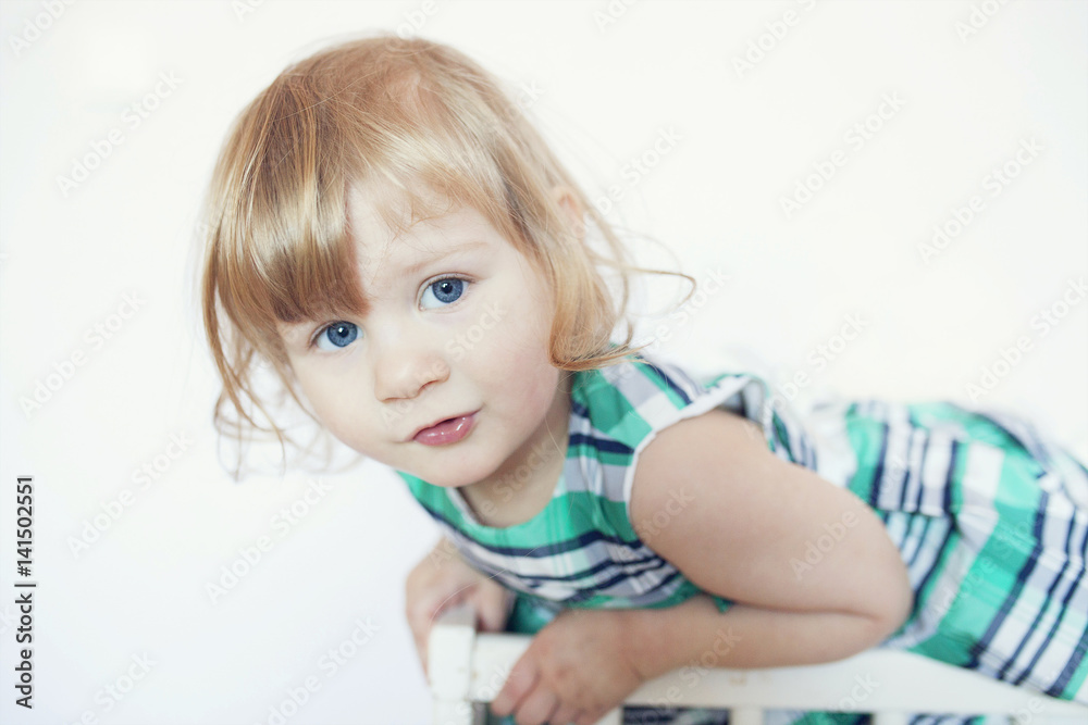 funny little girl leans over the railing of the bed funny little girl leans over the railing of the bed