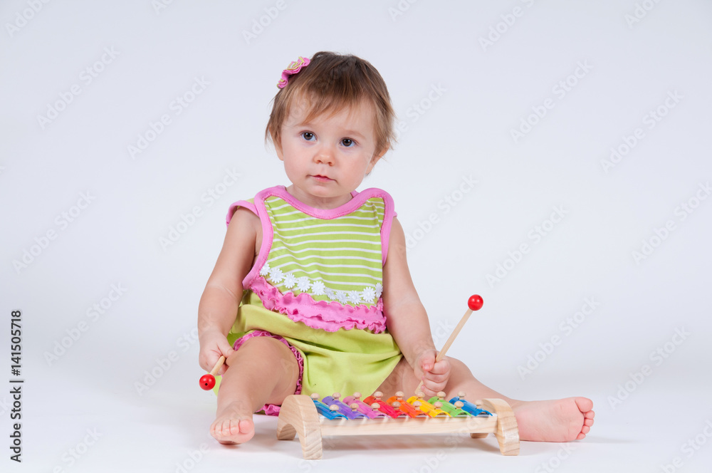 Girl with excitement playing on a xylophone isolated on white Girl with excitement playing on a xylophone isolated on white