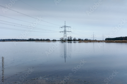reflection of electricity pylon in water against sky 
