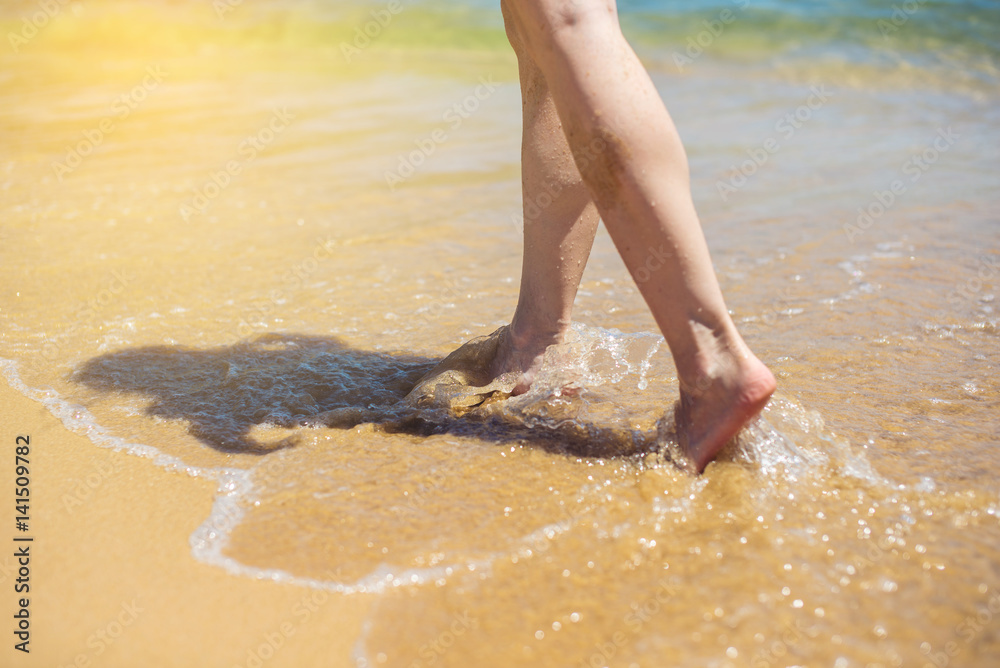 Woman walks barefoot in the sand washed by sea wave Woman walks barefoot in the sand washed by sea wave