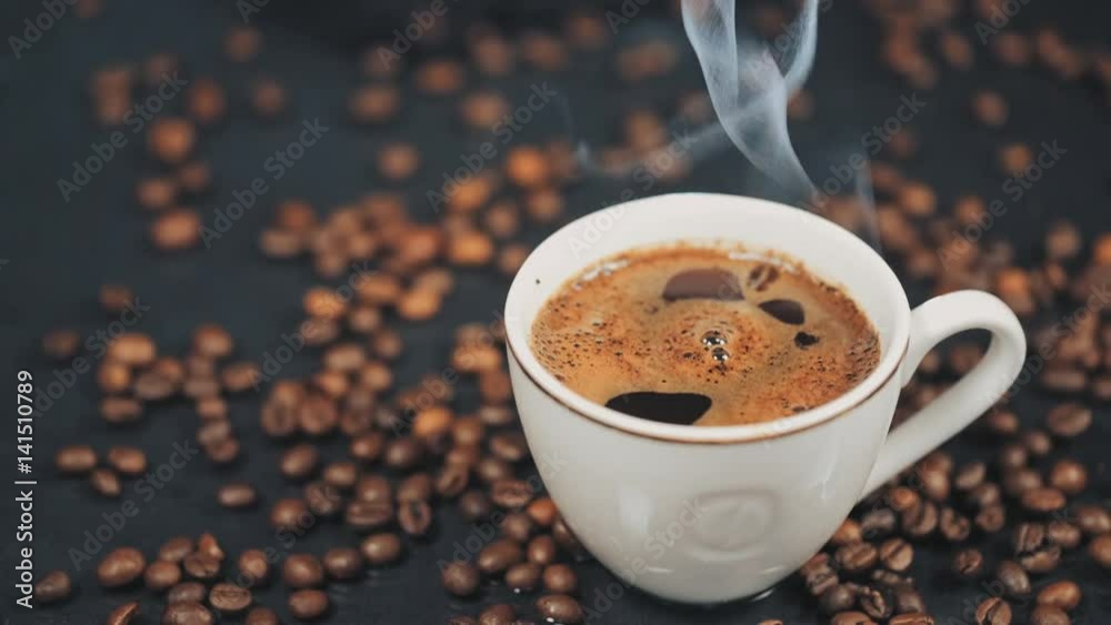 Cup of hot drink with steam over black background. Slow motion.
