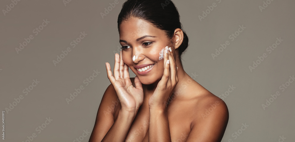 Beautiful woman applying cosmetic cream to her face Beautiful woman applying cosmetic cream to her face