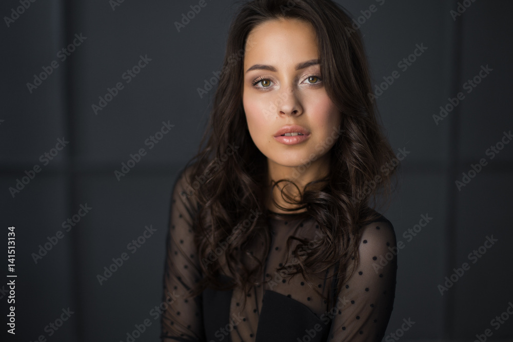Portrait of a young brunette sitting on the floor in a black bodysuit