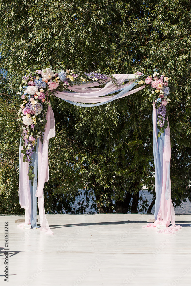 Beautiful wedding ceremony outdoors. Wedding arch made of cloth and white,  blue and pink flowers on a green natural background. Stock Photo | Adobe  Stock