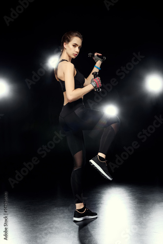 sportswoman doing exercises with dumbbells on black © LIGHTFIELD STUDIOS