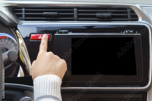 Foto woman finger pressing emergency button on car dashboard.