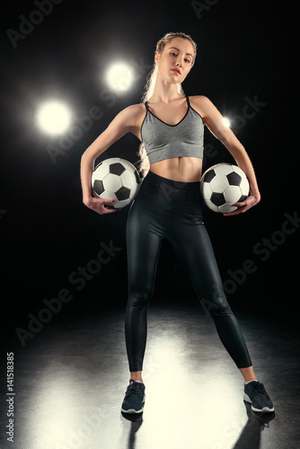 Confident beautiful young sportswoman posing with soccer balls