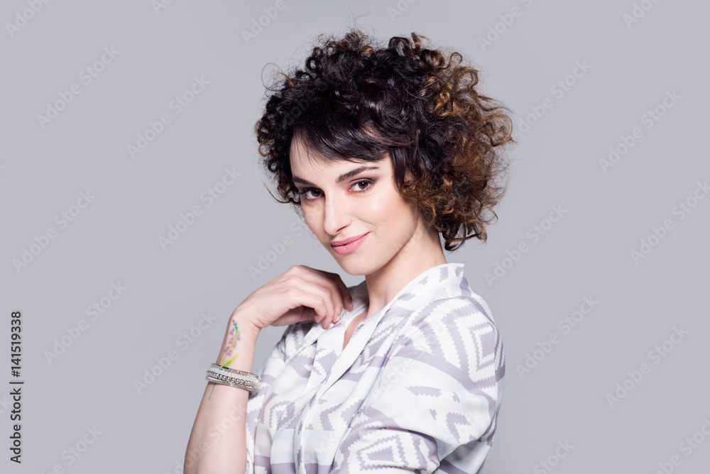 Beautiful woman with nice smile and afro hairstyle is standing on gray background