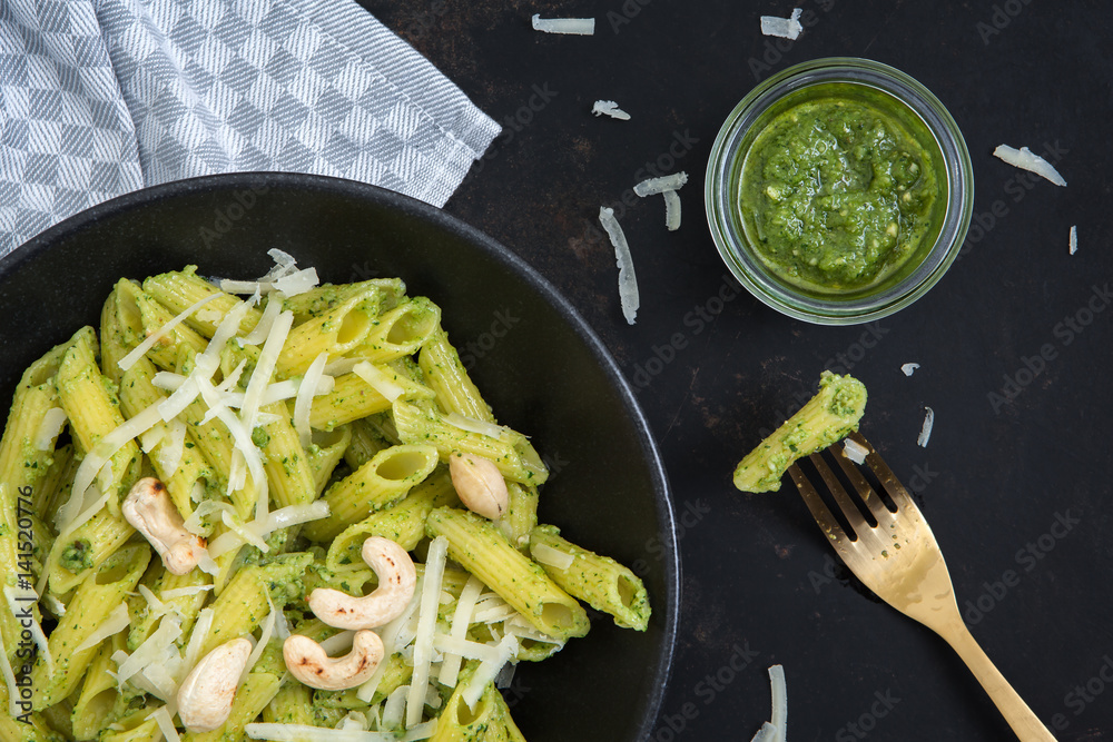 Teller mit Pennen und Pesto aus Radieschengrün auf einem alten Metalluntergrund
