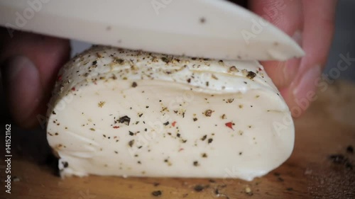 White Mozzarella cheese ball with cutted slices and pepper on wooden background close up macro cutting photo