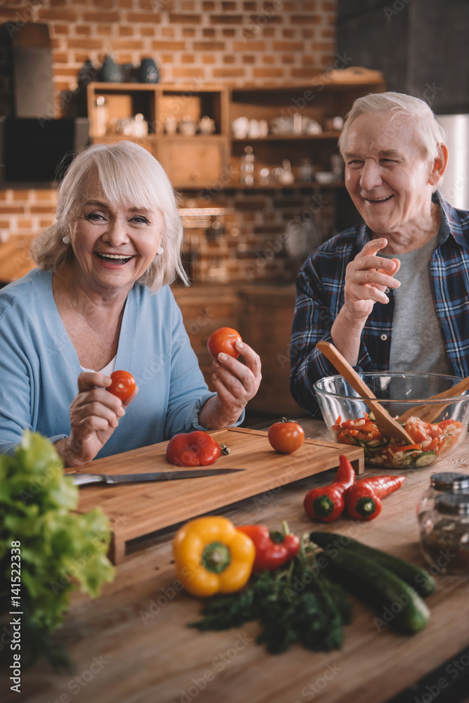 Happy senior couple cooking vegetable salad together Happy senior couple cooking vegetable salad together
