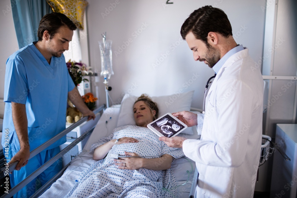 Male doctor looking at sonography report on a digital tablet Male doctor looking at sonography report on a digital tablet