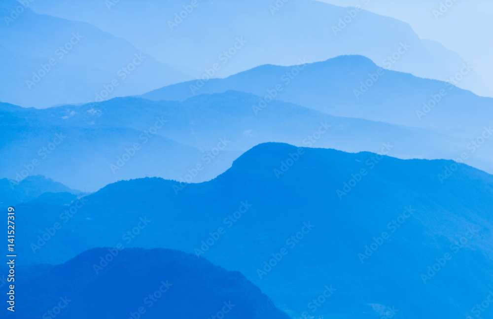 Aerial atmospheric perspective of blue mountain ranges background.