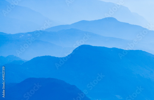 Aerial atmospheric perspective of blue mountain ranges background.