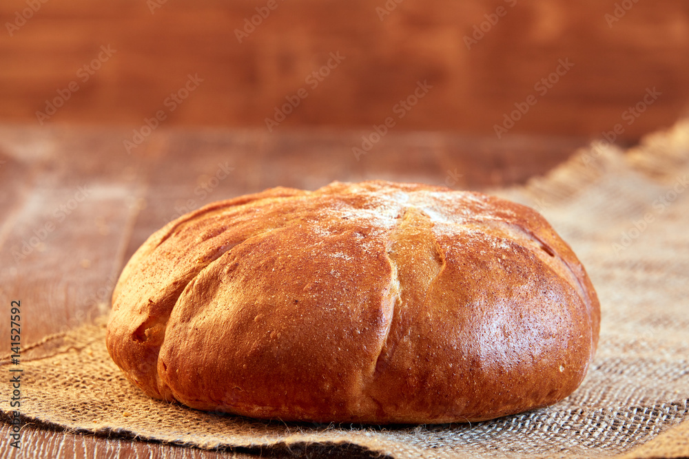 One white bread with flour on a wooden background. Advertising bread. Leaning flour.
