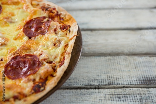 Italian pizza served in a tray on a wooden plank