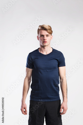 Handsome fitness man in blue t-shirt and shorts, studio shot.