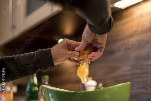 Φωτογραφία hands cracking an egg into bowl to make fresh waffles
