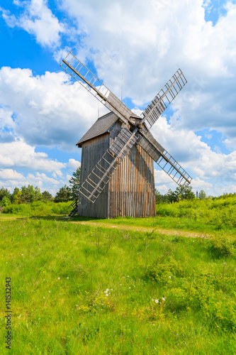 Old wooden windmill on green field in spring landscape of Tokarnia village, Poland