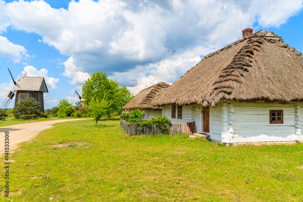 Old traditional houses with straw roof in Tokarnia village on sunny spring day, Poland