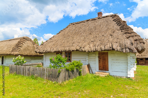 Old traditional house with straw roof in Tokarnia village on sunny spring day, Poland