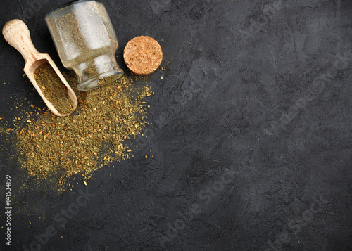 Zaatar - mix of Oriental spices on a dark stone background. Seasoning made from dried herbs, mixed with sesame seeds, sumac, salt and other spices. Top view.  Copy space. Selective focus photo