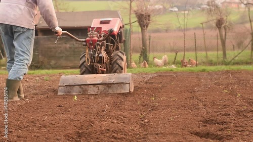 Farmer plowing the field with rototiller.  photo