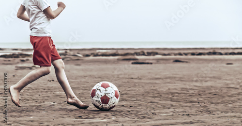 Child playing soccer on the beach photo