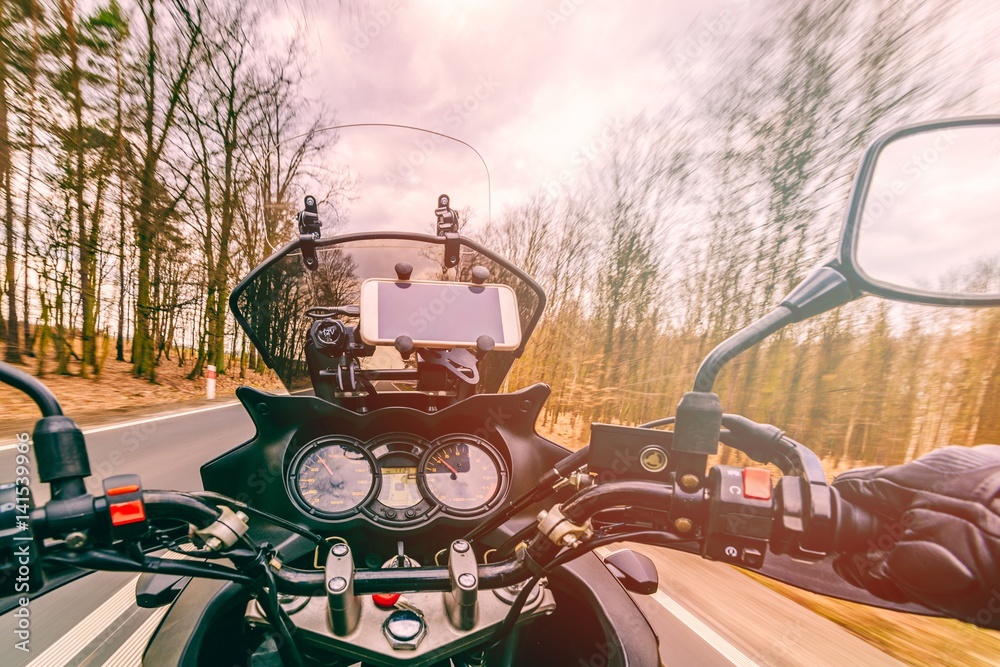 Naklejka premium Driving a motorcycle at spring at the asphalt road