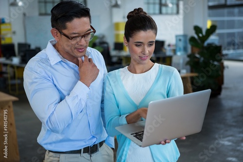 Business colleagues discussing over laptop