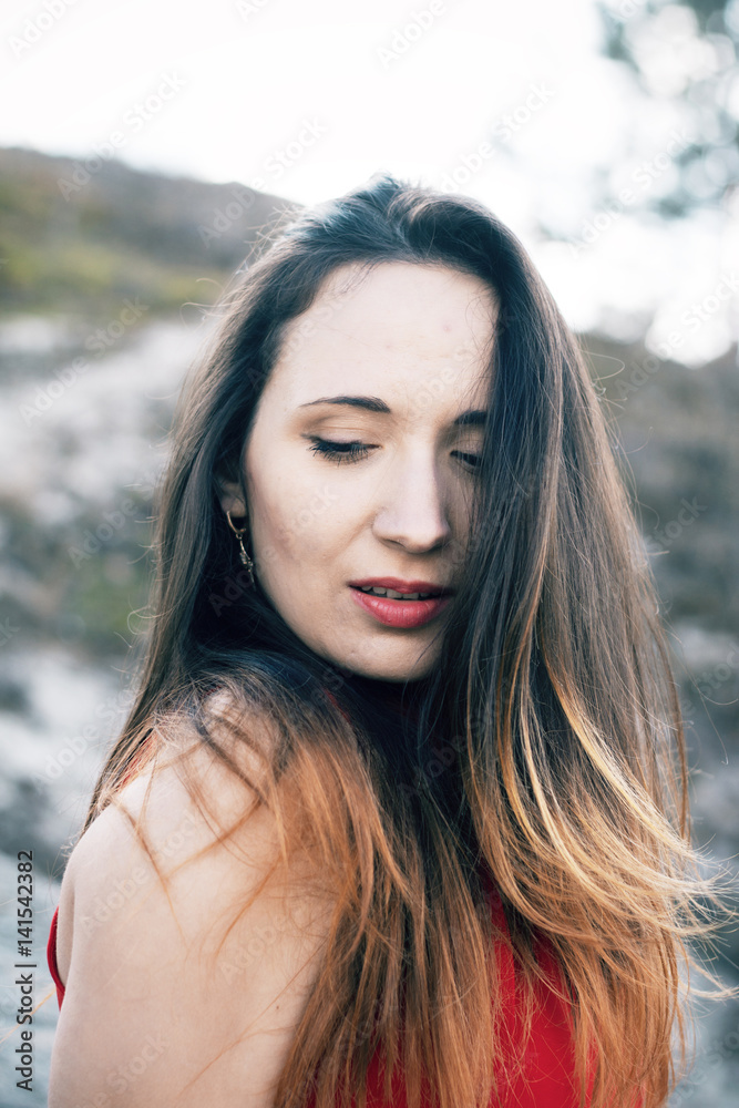 A girl in a red dress strolls through the forest