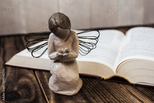 angel and bible on wooden background
