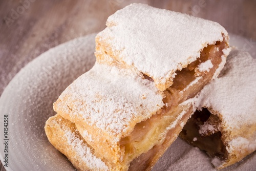 Detail of Two slices of apple strudel with powder sugar on white saucer
