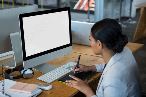 Female graphic designer using graphics tablet at desk