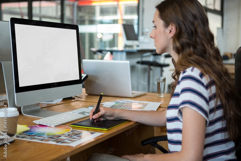 Female graphic designer using graphics tablet at desk Female graphic designer using graphics tablet at desk